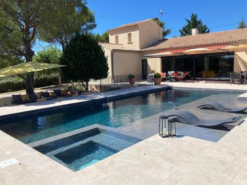une piscine avec des chaises et une maison dans l'établissement Thaliana, à Saumane-de-Vaucluse