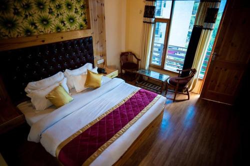 a bedroom with a large bed with yellow pillows at Timber Hill Hotel in Manāli