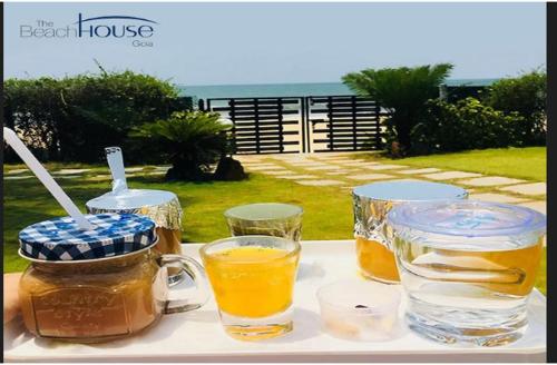 a table with two glasses and a jar of honey at Beach House Resort Goa in Benaulim