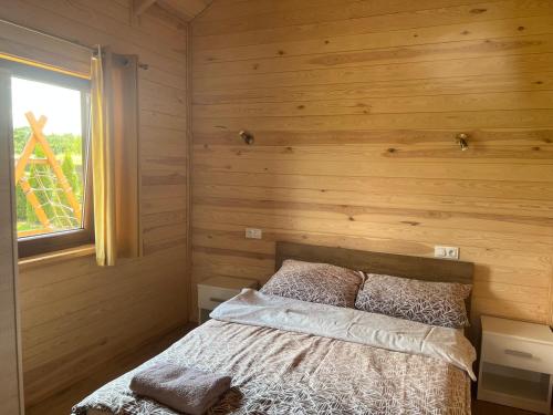 a bedroom with a bed in a wooden wall at Domki caloroczne Przytulisko na Mazurach in Ruciane-Nida