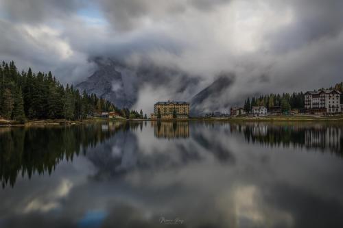 a reflection of a building on a lake with a mountain at Casetta sul Lago di Misurina in Misurina