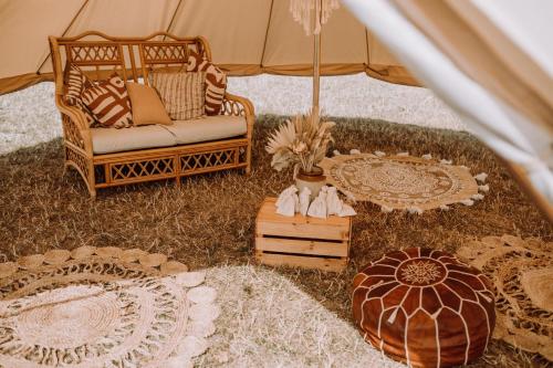 a tent with a chair and some rugs on the grass at Glamping at Beaumont Paddocks in St. Albans