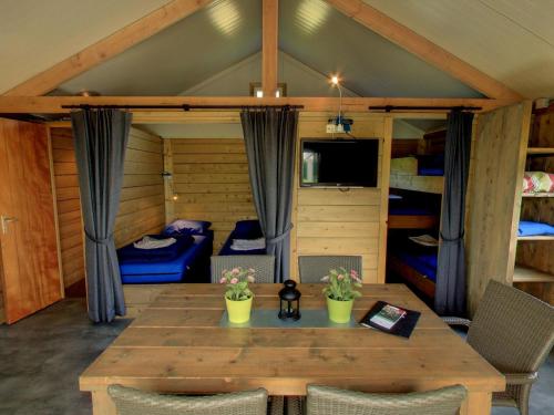 a room with a table and chairs and bunk beds at Cozy tentlodge with roofed terrace in a green area in IJhorst