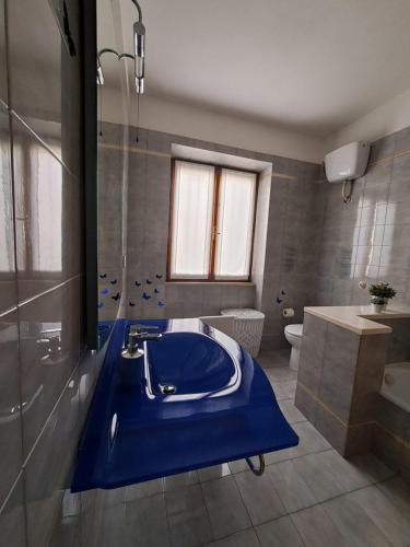 y baño con bañera azul y lavamanos. en Casa Ai giardini, en Gradoli
