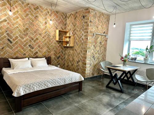 a bedroom with a brick wall with a bed and a table at Comfortable apartments in the city center, near the theater and Zlata Plaza in Rivne