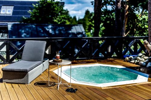 a hot tub on a deck with a chair and a table at Domki Osada Bacówka Radawa & SPA in Radawa