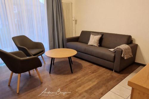 uma sala de estar com um sofá e duas cadeiras e uma mesa em Haus-Koenigsduene-II-10 em Borkum