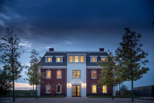 una casa grande con sus luces encendidas por la noche en Design apartment in Zeeland with its own wellness, en Colijnsplaat