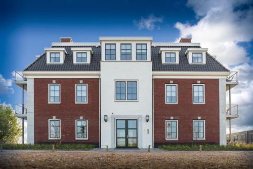 un gran edificio rojo y blanco en una calle en Design apartment in Zeeland with its own wellness, en Colijnsplaat