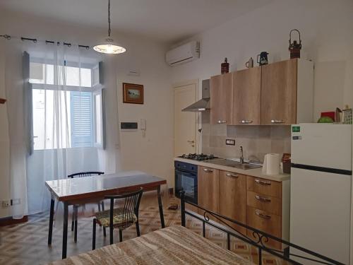 a kitchen with a table and a white refrigerator at "la casa dell'architetto" con terrazza panoramica in centro storico e a due passi dal porto in Lipari