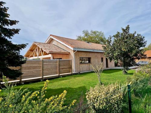 a wooden house with a fence and a yard at Belle Villa Terra Mare classée 4 étoiles entre océan et bassin in Lège-Cap-Ferret