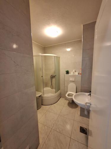 a bathroom with a shower and a toilet and a sink at Apartman Sarah - Autobuska Stanica in Tuzla