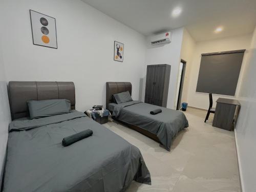 een kamer met 2 bedden en een flatscreen-tv bij Elonna Homestay in Jerantut