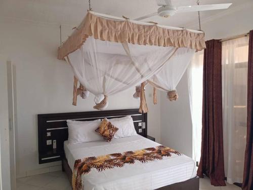 a bedroom with a bed with a canopy and a window at Becky Homes Diani Beach - 2BR with AC & Pool in Diani Beach