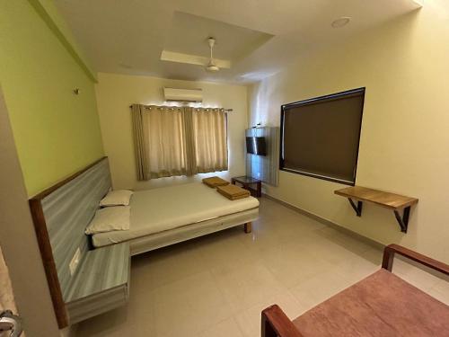 a room with a couch and a tv in it at Hotel Aaba's Gomantak in Sawantwadi