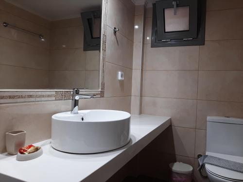 a bathroom with a white sink and a toilet at Sirena Apartments in Agia Pelagia