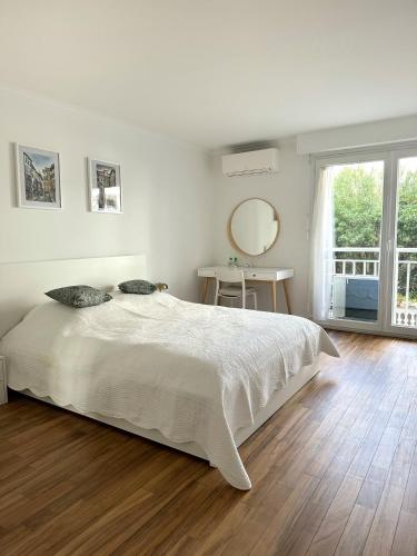 une chambre blanche avec un grand lit et un miroir dans l'établissement Appartement rénové CANNES, palm beach, à Cannes