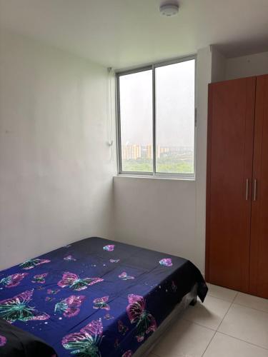 um quarto com uma cama com um edredão azul e uma janela em Apartamento con excelentes comodidades em Cúcuta