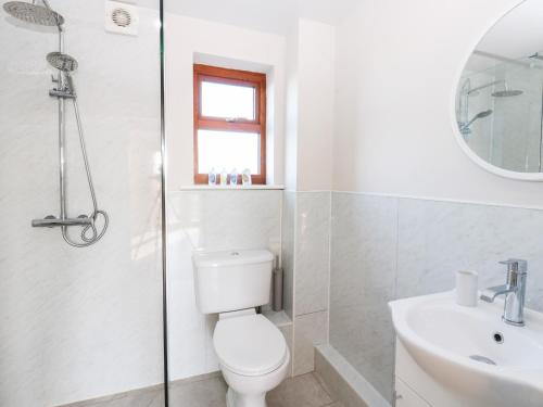 a white bathroom with a toilet and a sink at Elder Cottage in Richmond