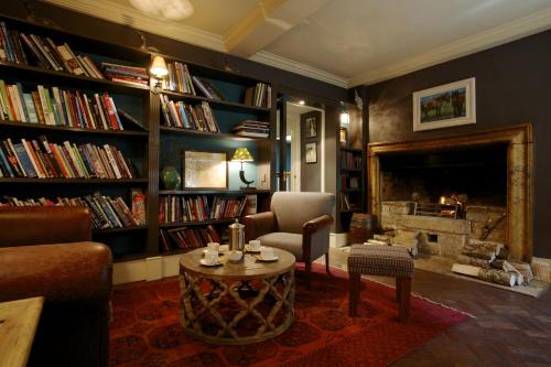 a living room with a fireplace and a couch and a table at The Bay Tree Hotel in Burford