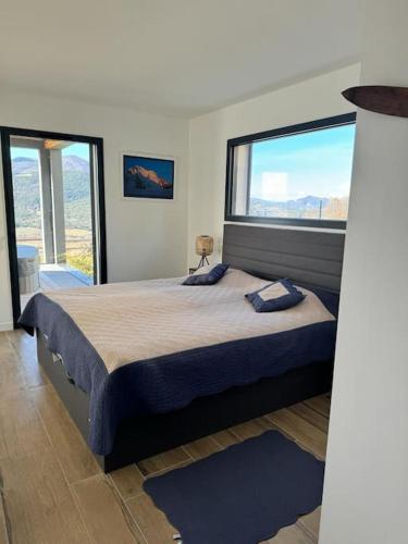 une chambre avec un grand lit avec une grande fenêtre dans l'établissement maison lac et montagne, à Chorges