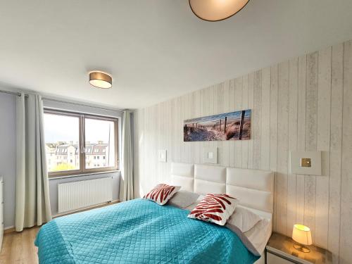 シフィノウイシチェにあるvisit baltic - Róży Wiatrówのベッドルーム1室(青い毛布付きのベッド1台付)