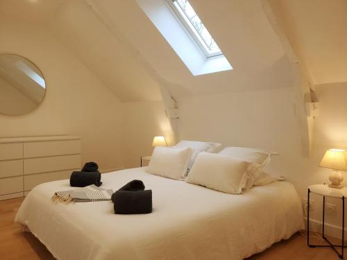 een slaapkamer met een groot wit bed met 2 stoelen erop bij Gîte de charme XIXe in Grand-Champ