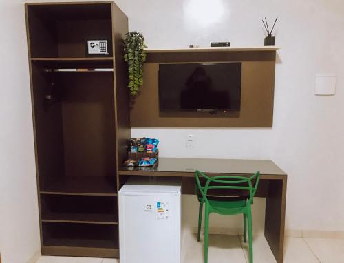 une chaise verte assise à côté d'un bureau avec une télévision dans l'établissement HOTEL VIANA, à Barra do Corda
