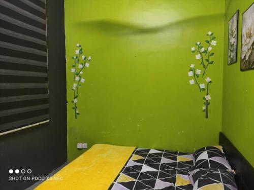 a bedroom with a green wall with flowers on it at DSR homestay in Kuantan