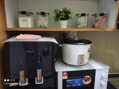 a kitchen with a microwave and a toaster and a slow cooker at DSR homestay in Kuantan