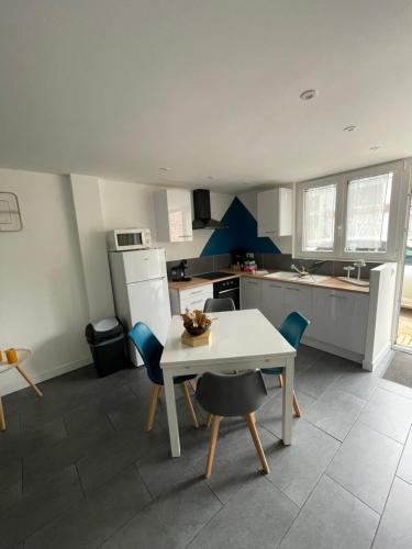 une cuisine avec une table blanche et des chaises bleues. dans l'établissement maison de ville en centre ville cany-barville, à Cany-Barville