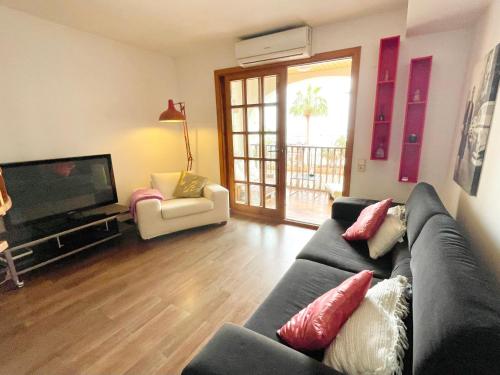 a living room with a couch and a television at Ensuite Double Room with Terrace in Shared Apartment in center of Santa Eularia with Sea View and Close to the Beach in Santa Eularia des Riu