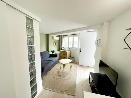 un salon avec un canapé bleu et une table dans l'établissement Studio Rochereau Climatisé - Metro - Gare - Wifi, à Toulouse