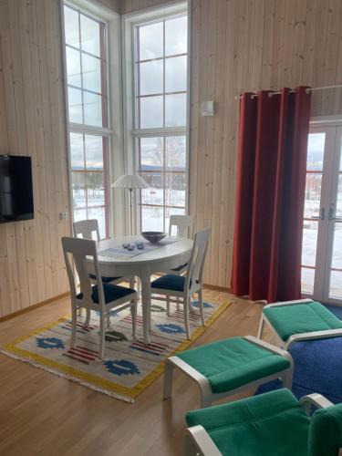 a dining room with a table and chairs and windows at Tällberg, utsikt över Siljan in Leksand