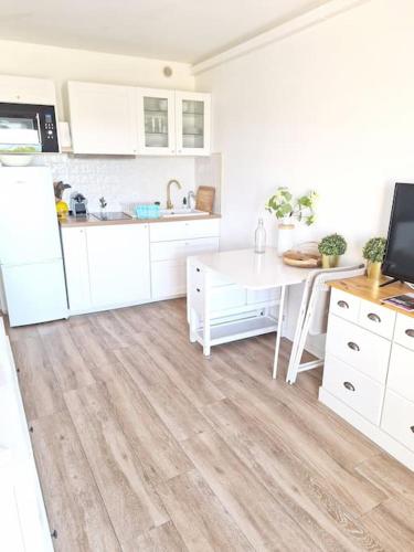 une cuisine avec des armoires blanches et un plancher en bois dans l'établissement Coquet appartement rénové vue étangs, à Palavas-les-Flots