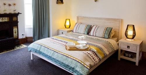 a bedroom with a bed with two tables and two lamps at Artica Art & Accommodation in Dunedin