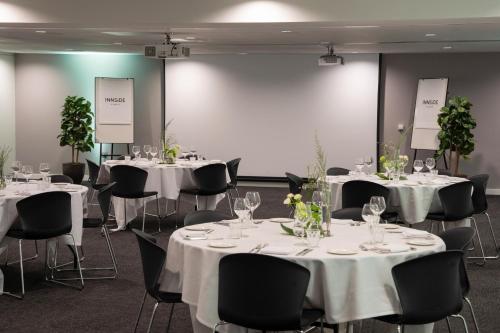 a room with tables and chairs with white tablecloths at INNSiDE by Meliá Newcastle in Newcastle upon Tyne