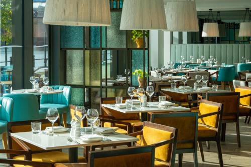 a restaurant with tables and chairs and windows at INNSiDE by Meliá Newcastle in Newcastle upon Tyne