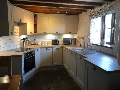 a kitchen with white cabinets and a sink and a stove at The Granary in Bridgend