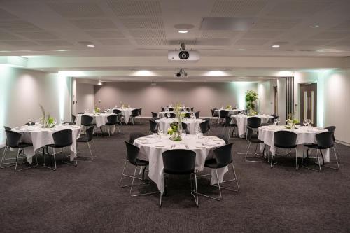 a banquet room with white tables and chairs with flowers on them at INNSiDE by Meliá Newcastle in Newcastle upon Tyne