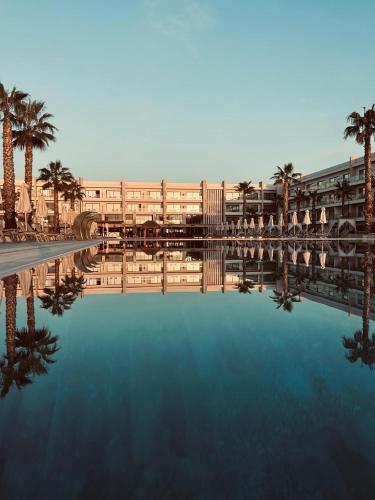 a pool of water with palm trees and a building at Boo_Apartment in Draç