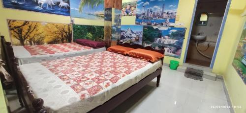 two beds in a room with paintings on the walls at Sri bagavan lodge in Tiruvannāmalai