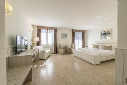 a living room with a white couch and a television at Hotel Golf Inn in Lignano Sabbiadoro