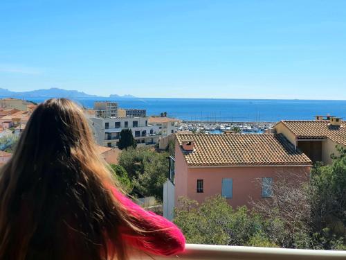 a woman looking at the city from a balcony at L'escapade Côte Bleue vue mer panoramique in Sausset-les-Pins