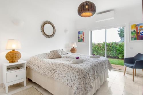 een witte slaapkamer met een bed en een raam bij Casa Rosella in Carvoeiro