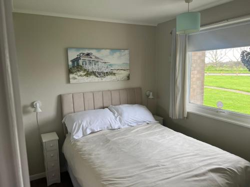 een slaapkamer met een wit bed en een raam bij LA BELLA CHALETS 2 - 155 Sunbeach Holiday Village Scratby in Scratby