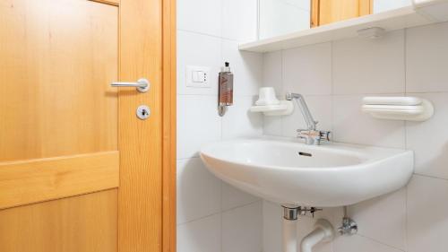 een badkamer met een witte wastafel naast een deur bij Bruni 2 in Bormio