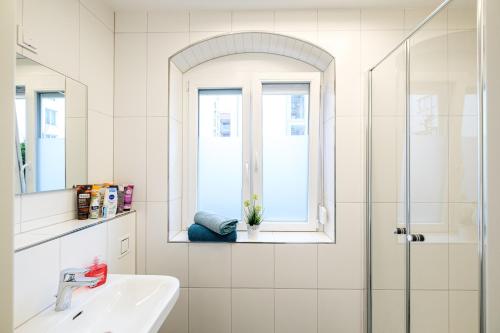 a bathroom with a sink and a shower with a window at Ulmer Stadtwohnung in Ulm