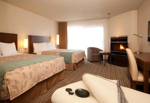 a hotel room with two beds and a fireplace at Excelsior Hôtel Spa Sainte-Adèle in Sainte-Adèle