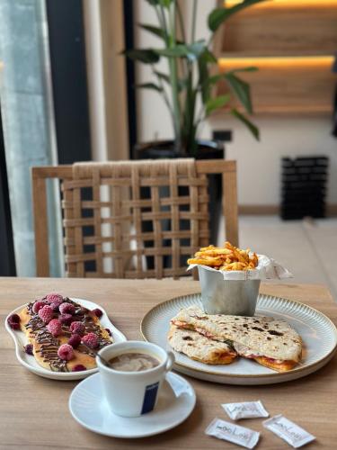 a table with two plates of food and cups of coffee at Hotel 1920 in Podgorica